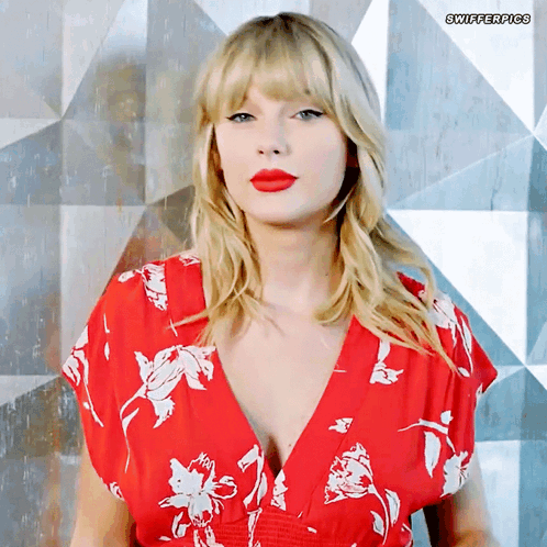A Woman Wearing A Red Floral Dress With Swifterpics Written On The Bottom Right GIF