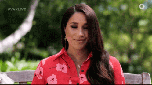 A Woman Wearing A Red Floral Shirt Is Sitting On A Bench . GIF