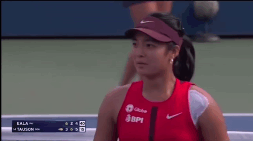 A Woman Wearing A Red Shirt That Says Bpi Is Smiling On A Tennis Court GIF