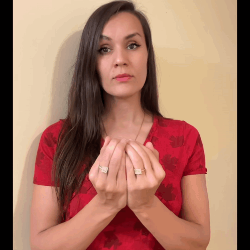 A Woman Wearing A Red Shirt With Leaves On It Is Holding Her Hands Together GIF