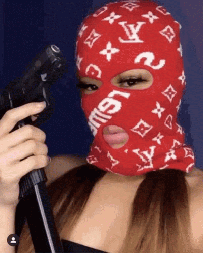 A Woman Wearing A Red Ski Mask Is Holding A Gun GIF