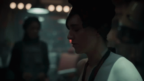 A Woman Wearing A Scarf Around Her Head Looks To The Side GIF