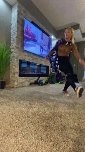 A Woman Wearing A Scarf That Says ' Oakland ' On It Is Jumping In Front Of A Television GIF