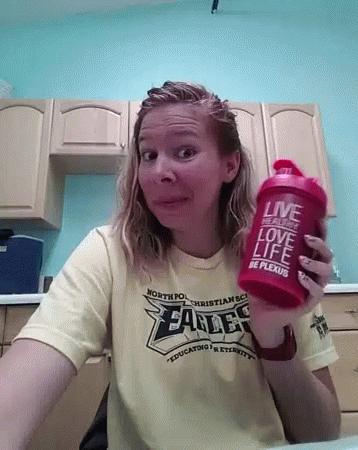 A Woman Wearing A Shirt That Says Eagles Is Holding A Red Shaker GIF