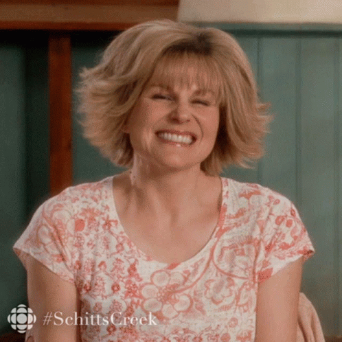 A Woman Wearing A Shirt That Says Schitts Creek Smiles GIF
