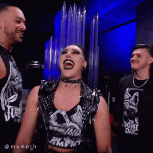 A Woman Wearing A Shirt That Says ' The Dogme Day ' Is Laughing With Two Men GIF