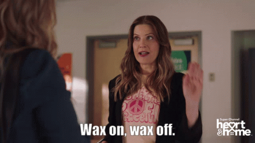 A Woman Wearing A Shirt That Says " Wax On Wax Off " Is Talking To Another Woman GIF