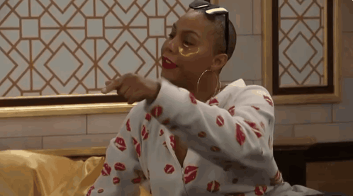 A Woman Wearing A Shirt With Kisses On It Is Pointing At Something GIF