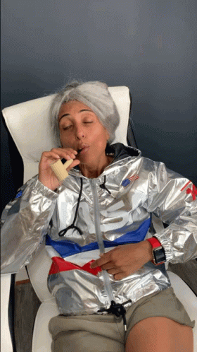 a woman wearing a silver nike jacket is smoking an electronic cigarette