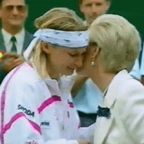 a woman wearing a skoda jacket is kissing another woman on the cheek