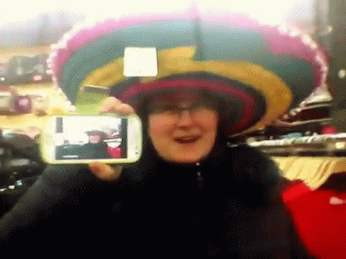 A Woman Wearing A Sombrero Is Taking A Picture Of Herself With A Cell Phone GIF