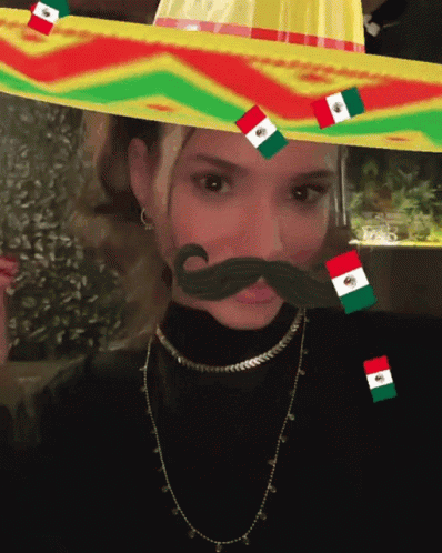 A Woman Wearing A Sombrero With Flags On It GIF