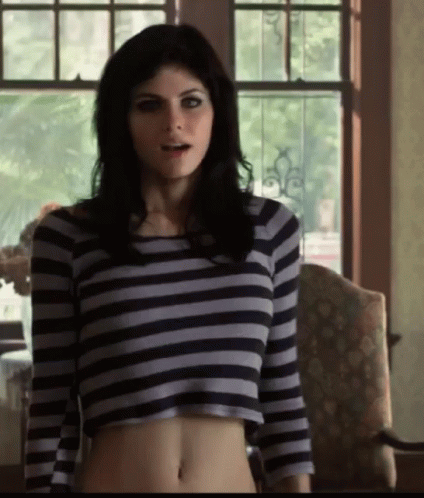 A Woman Wearing A Striped Crop Top Stands In Front Of A Window GIF