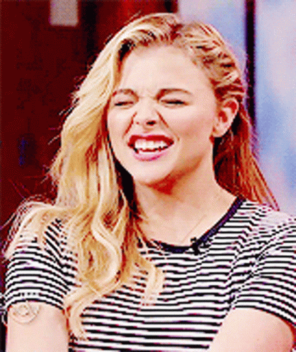 A Woman Wearing A Striped Shirt Is Making A Funny Face . GIF