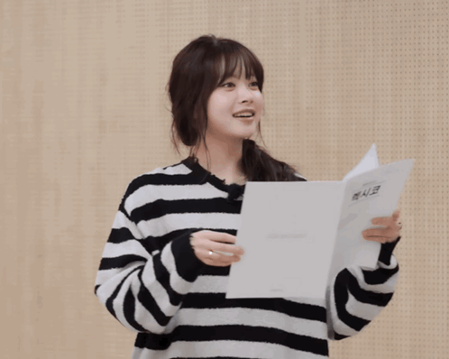 A Woman Wearing A Striped Sweater Holds A Piece Of Paper And Says Gracias In A Foreign Language GIF