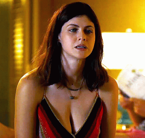 A Woman Wearing A Striped Top And A Necklace Is Sitting In A Room . GIF