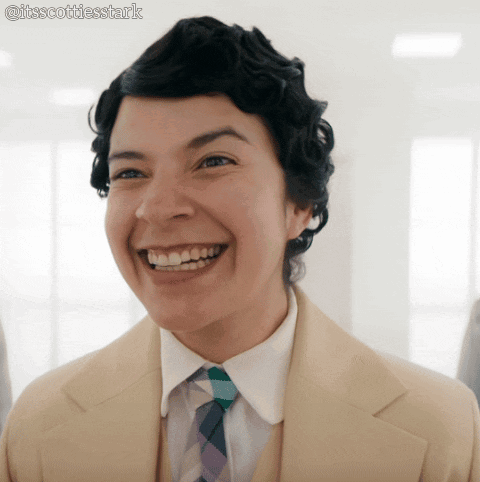 A Woman Wearing A Suit And Tie Is Smiling With The Hashtag Itsscottiesstark GIF