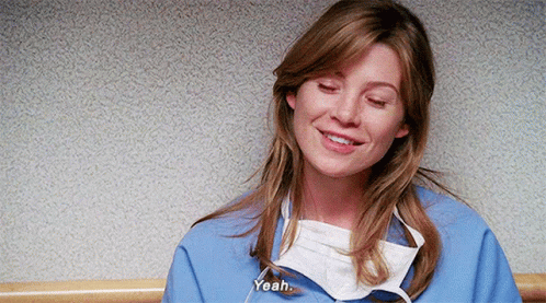 A Woman Wearing A Surgical Mask And A Blue Scrub Is Smiling And Talking . GIF