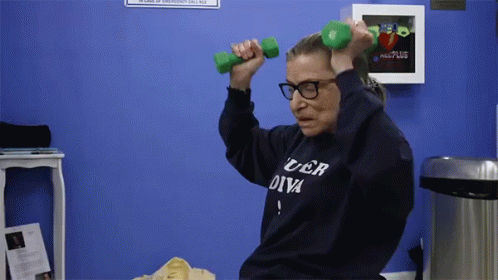 A Woman Wearing A Sweater That Says Uber Diva Is Lifting Dumbbells GIF