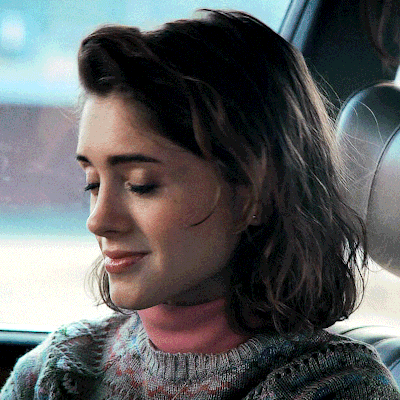 A Woman Wearing A Sweater With A Pink Turtleneck Is Smiling GIF