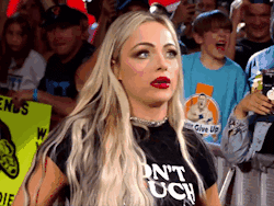 A Woman Wearing A T-Shirt That Says " Do N't Touch " Is Standing In Front Of A Crowd GIF