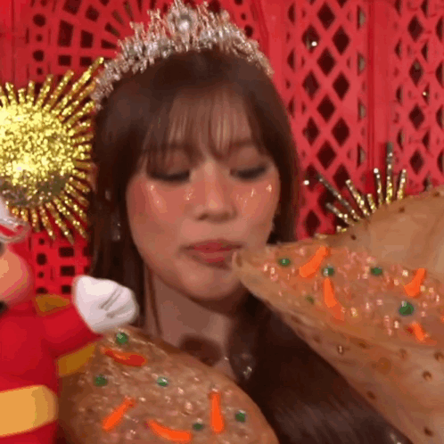 A Woman Wearing A Tiara And A Crown Is Eating A Pizza GIF
