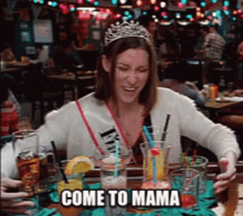 A Woman Wearing A Tiara Is Sitting At A Table With Drinks And The Words Come To Mama Below Her GIF