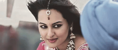 A Woman Wearing A Turban And Earrings Is Looking At A Man . GIF