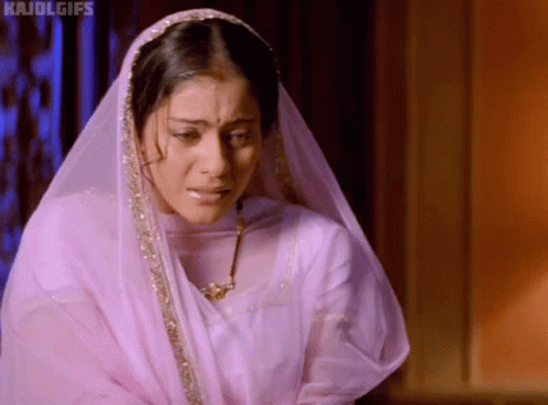 A Woman Wearing A Veil And A Necklace Is Crying And Looking Down . GIF