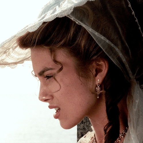 A Woman Wearing A Veil And Earrings Looks Down GIF