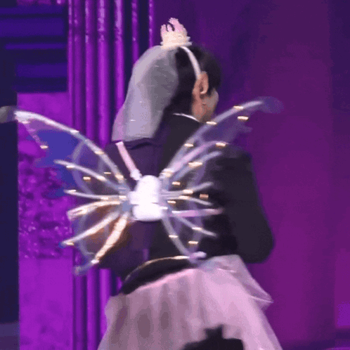 A Woman Wearing A Veil And Wings On A Stage GIF