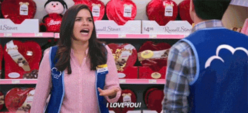 a woman wearing a vest that says i love you is talking to a man