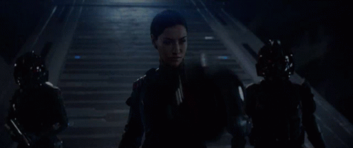 A Woman Wearing A Virtual Reality Headset Stands In A Dark Room GIF
