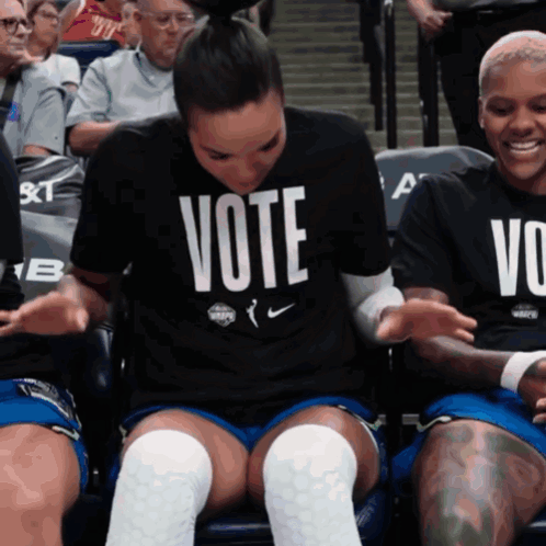 A Woman Wearing A Vote Shirt Sits In A Crowd GIF