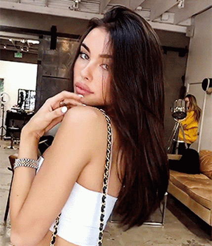 A Woman Wearing A White Crop Top With A Gold Chain Shoulder Strap GIF