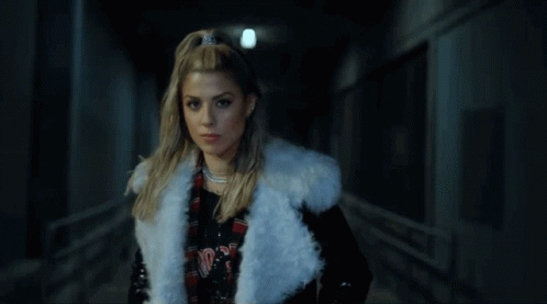 A Woman Wearing A White Fur Coat And A Plaid Shirt With The Word Nirvana On It GIF