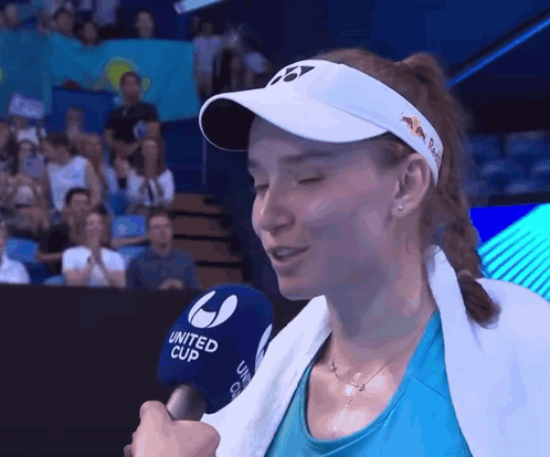 A Woman Wearing A White Hat And A Blue Shirt Is Talking Into A United Cup Microphone GIF