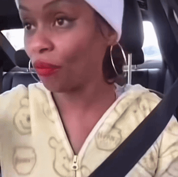 A Woman Wearing A White Headband And Hoop Earrings Is Sitting In The Back Seat Of A Car GIF