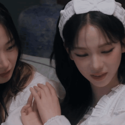 A Woman Wearing A White Headband With A Bow Is Holding Another Woman 'S Hand GIF