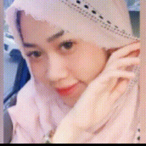 A Woman Wearing A White Hijab And A White Jacket Is Talking On A Cell Phone . GIF