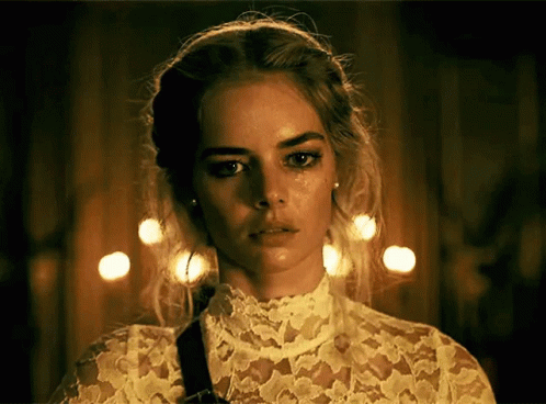 A Woman Wearing A White Lace Top Has A Tear Running Down Her Face GIF
