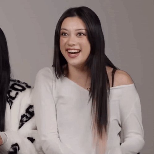 A Woman Wearing A White Off The Shoulder Sweater With The Letters Cc On It GIF