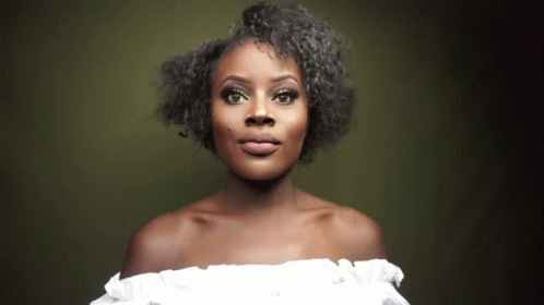 A Woman Wearing A White Off The Shoulder Top Is Looking At The Camera GIF
