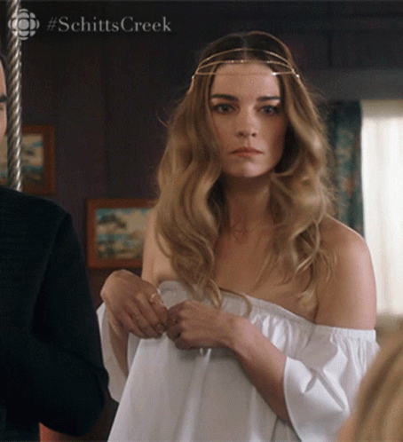 Woman In White Off-Shoulder Top Next To Man With Schitts Creek GIF