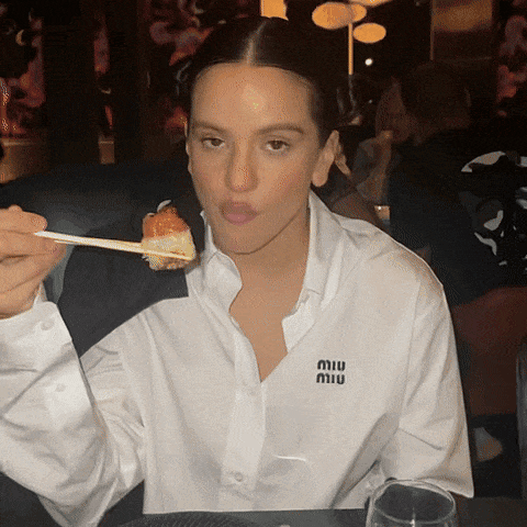 A Woman Wearing A White Shirt With A Miu Logo On It GIF