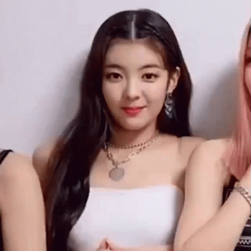A Woman Wearing A White Strapless Top And A Necklace Is Standing Next To Two Other Women . GIF