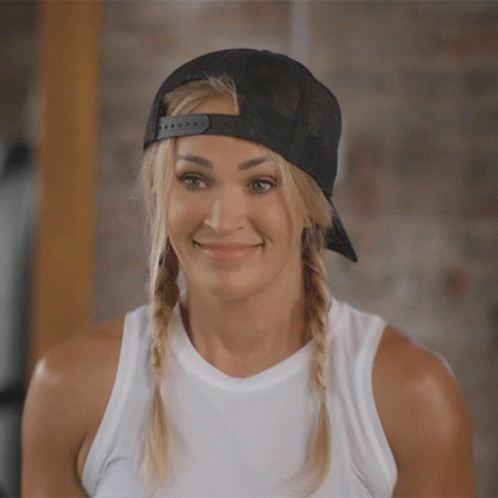 A Woman Wearing A White Tank Top And A Black Hat Is Smiling GIF