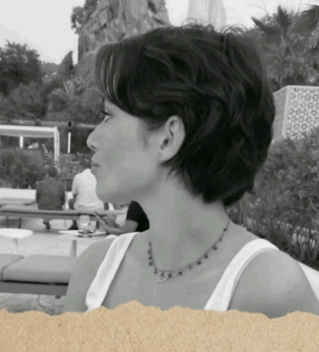 A Woman Wearing A White Tank Top And A Necklace GIF