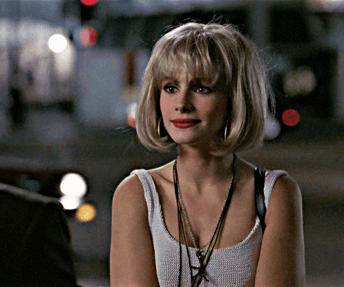 A Woman Wearing A White Tank Top With A Necklace Around Her Neck GIF