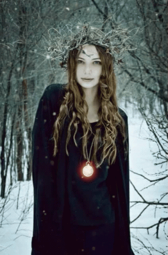 A Woman Wearing A Wreath Of Branches And A Necklace With A Coin On It GIF